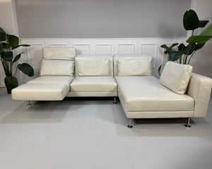 Gebrauchtes weißes Brühl Moule Designer Leder Sofa vor einer Wand, stilvoll und modern eingerichtet.