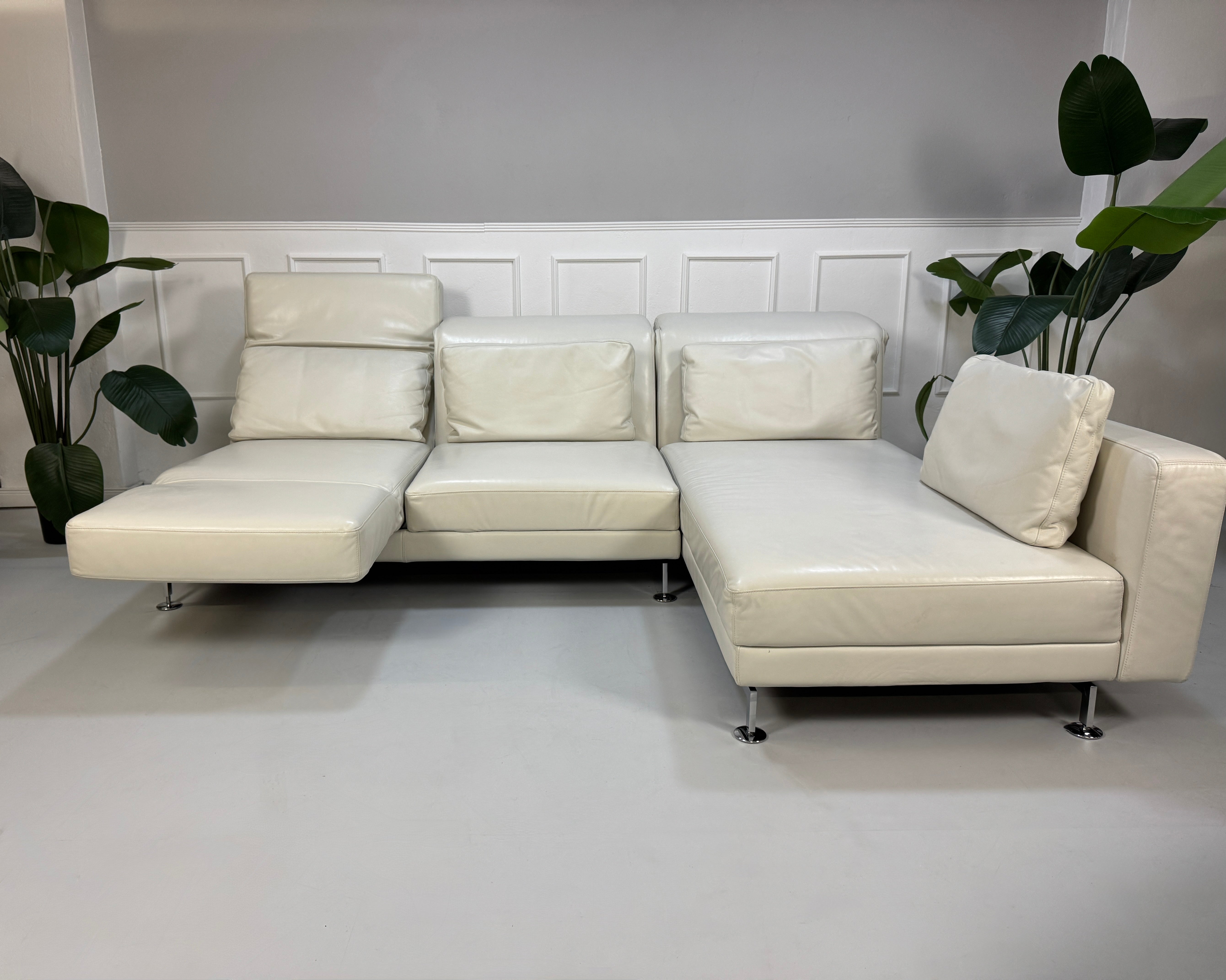 Gebrauchtes weißes Brühl Moule Designer Leder Sofa vor einer Wand, stilvoll und modern eingerichtet.