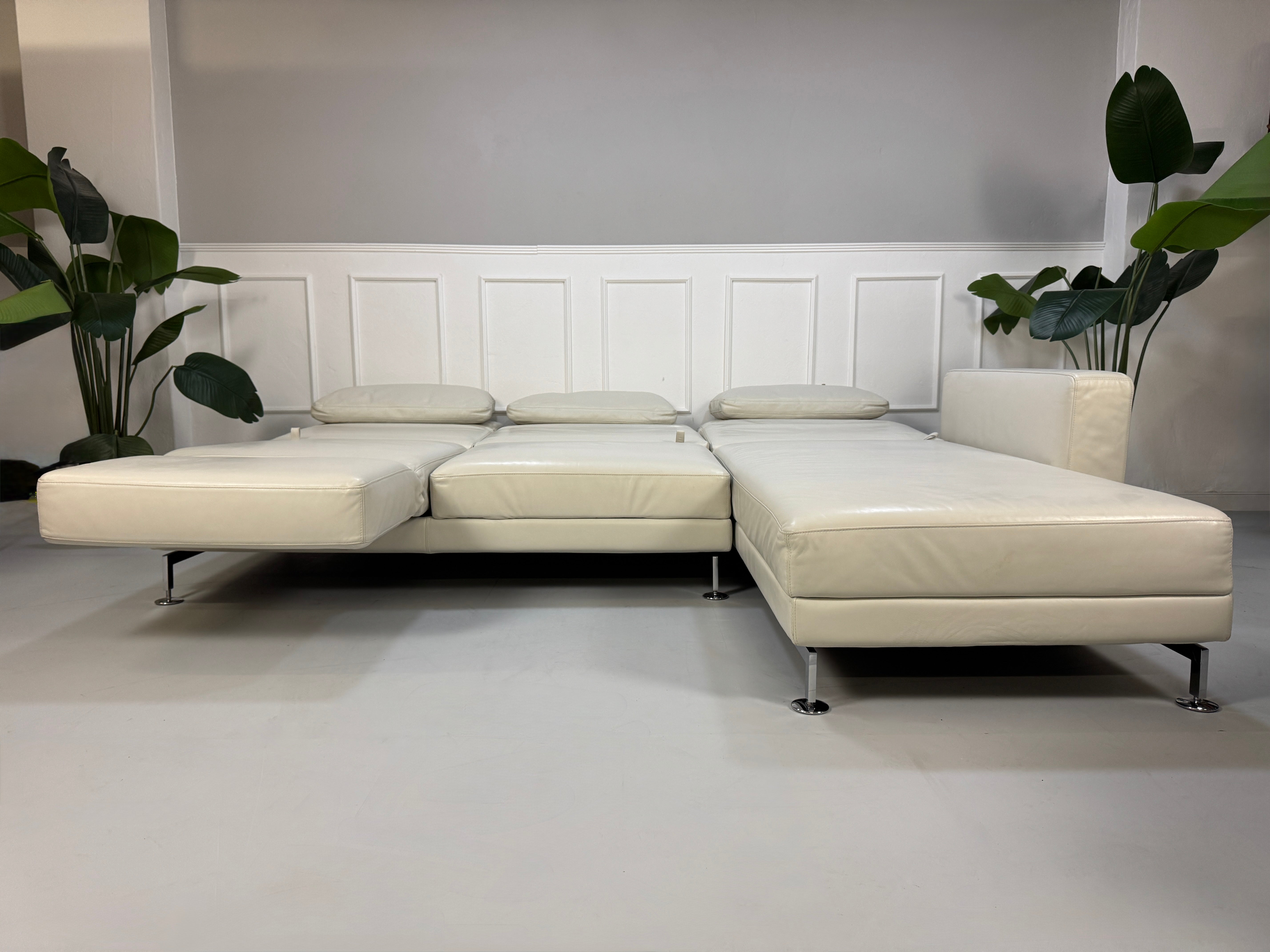Gebrauchtes weißes Brühl Moule Designer Leder Sofa vor einer Wand, stilvoll und modern eingerichtet.