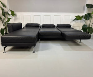 Gebrauchtes schwarzes Brühl Moule Designer Leder Sofa vor einer Wand, stilvoll und modern eingerichtet.
