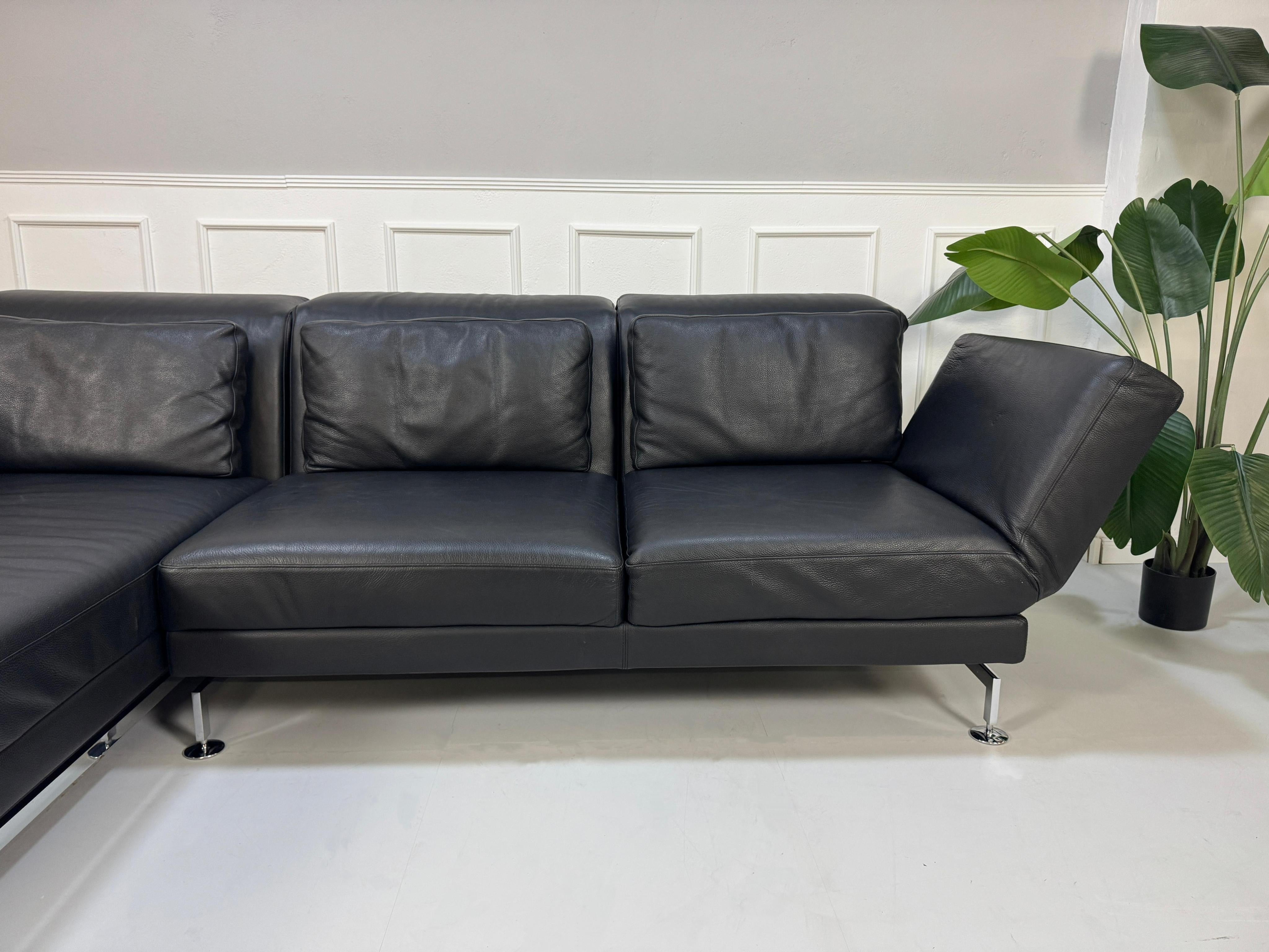 Gebrauchtes schwarzes Brühl Moule Designer Leder Sofa vor einer Wand, stilvoll und modern eingerichtet.