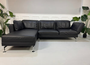 Gebrauchtes schwarzes Brühl Moule Designer Leder Sofa vor einer Wand, stilvoll und modern eingerichtet.
