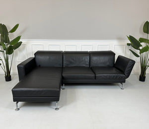 Gebrauchtes schwarzes Brühl Moule Designer Leder Sofa vor einer Wand, stilvoll und modern eingerichtet.