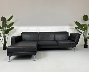 Gebrauchtes schwarzes Brühl Moule Designer Leder Sofa vor einer Wand, stilvoll und modern eingerichtet.