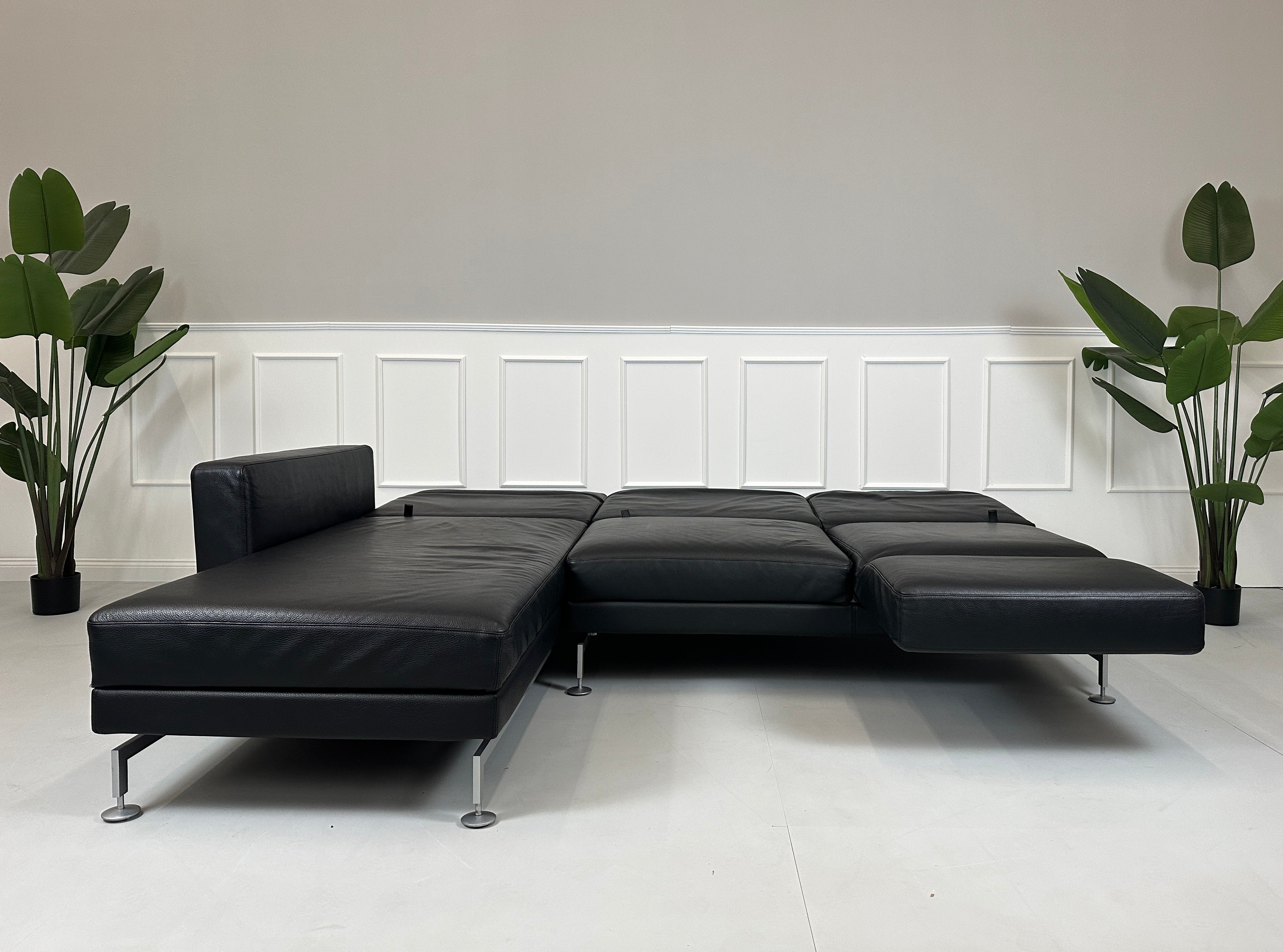 Gebrauchtes schwarzes Brühl Moule Designer Leder Sofa vor einer Wand, stilvoll und modern eingerichtet.