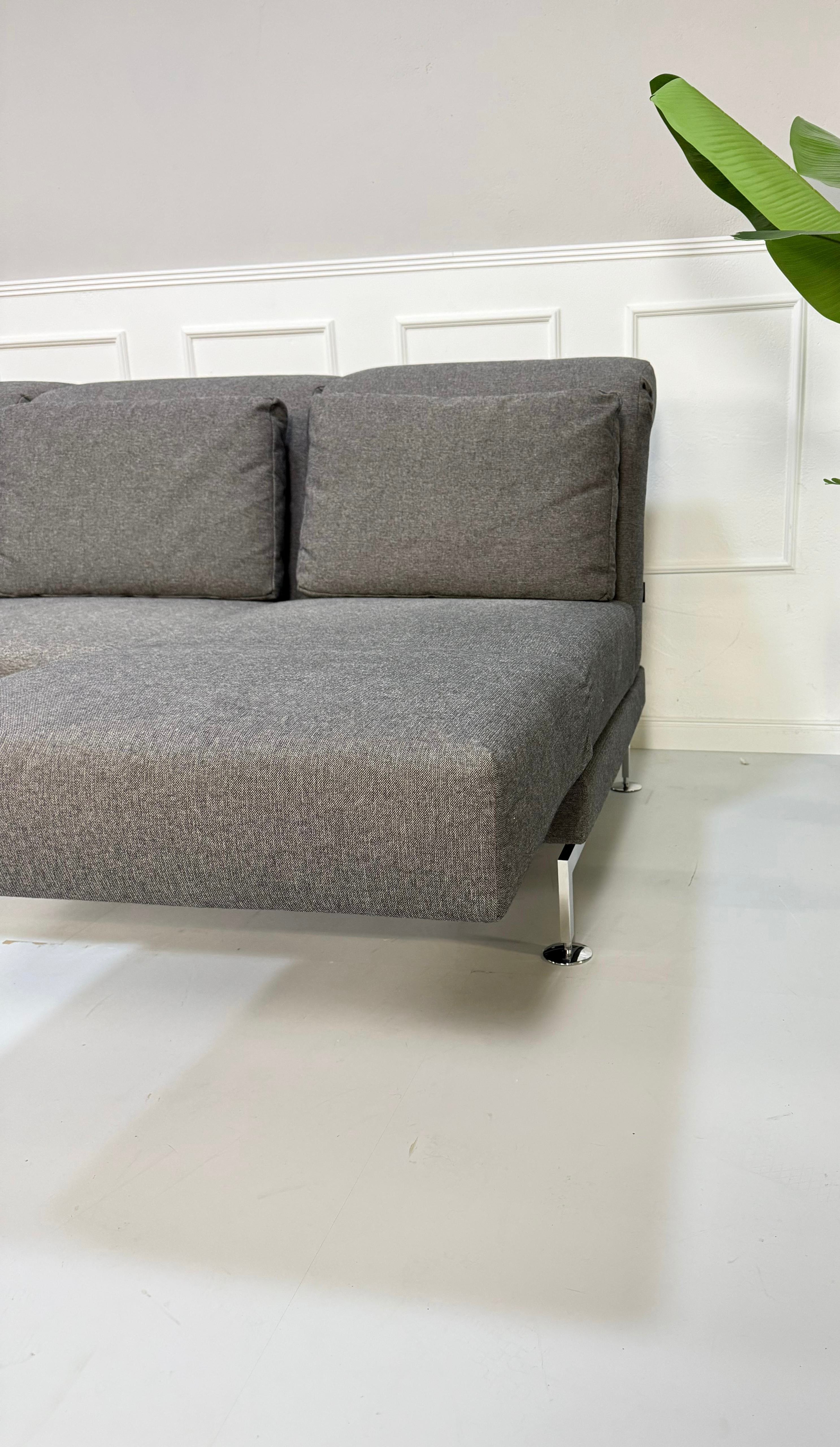 Gebrauchtes graues Brühl Moule Small Designer Stoff Sofa vor einer Wand, stilvoll und modern eingerichtet.