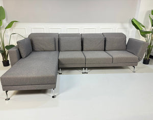 Gebrauchtes graues Brühl Moule Small Designer Stoff Sofa vor einer Wand, stilvoll und modern eingerichtet.