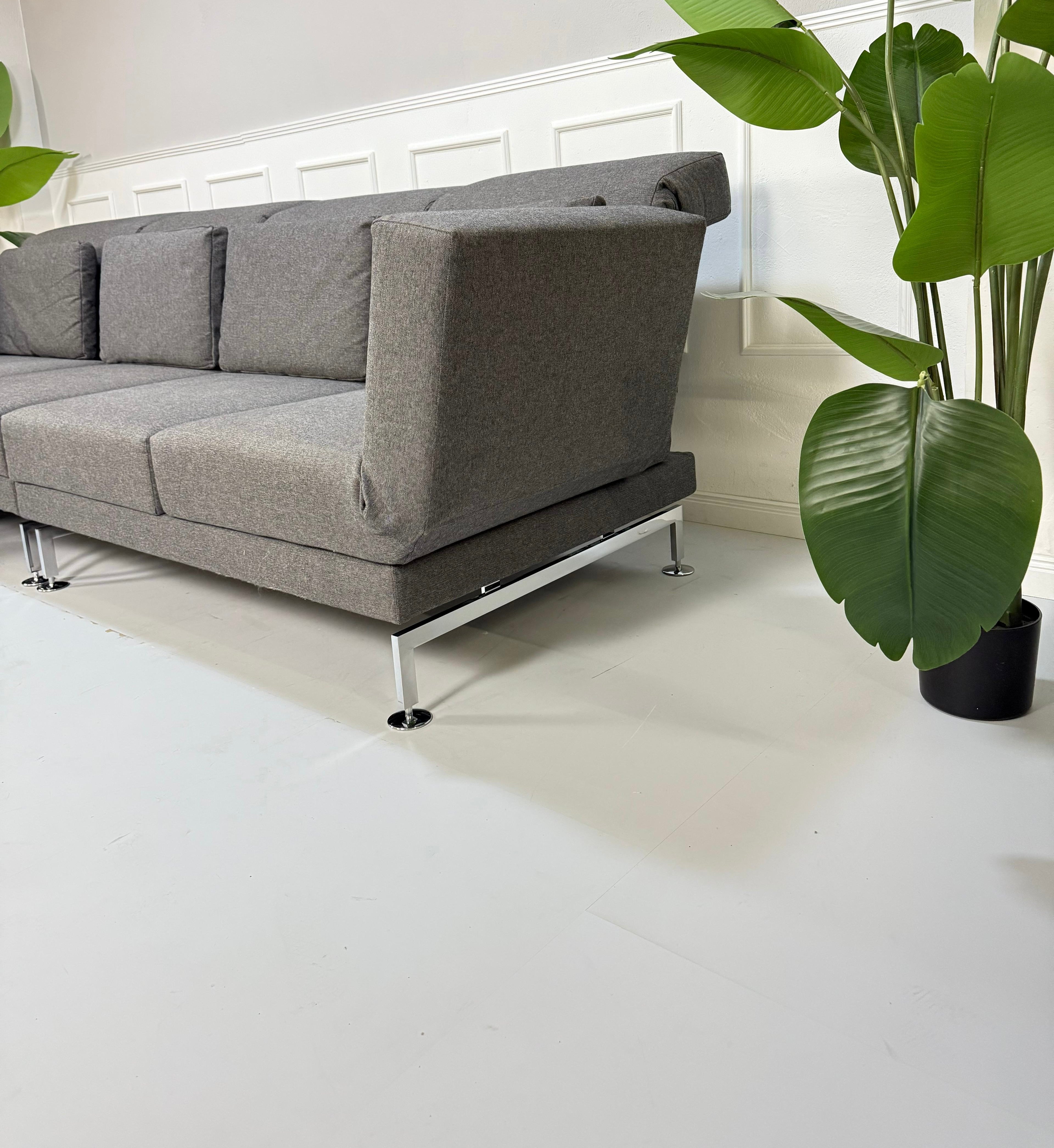 Gebrauchtes graues Brühl Moule Small Designer Stoff Sofa vor einer Wand, stilvoll und modern eingerichtet.