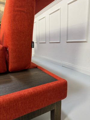 Gebrauchtes orangen Brühl Moule Small Designer Stoff Sofa vor einer Wand, stilvoll und modern eingerichtet.