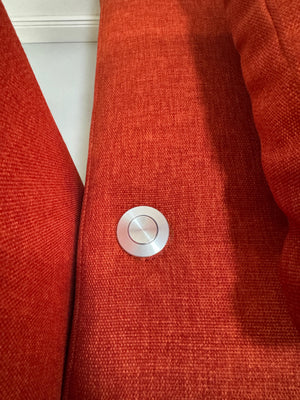 Gebrauchtes orangen Brühl Moule Small Designer Stoff Sofa vor einer Wand, stilvoll und modern eingerichtet.