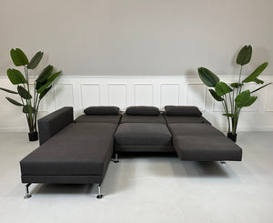 Gebrauchtes lila Brühl Moule Designer Stoff Sofa vor einer Wand, stilvoll und modern eingerichtet.