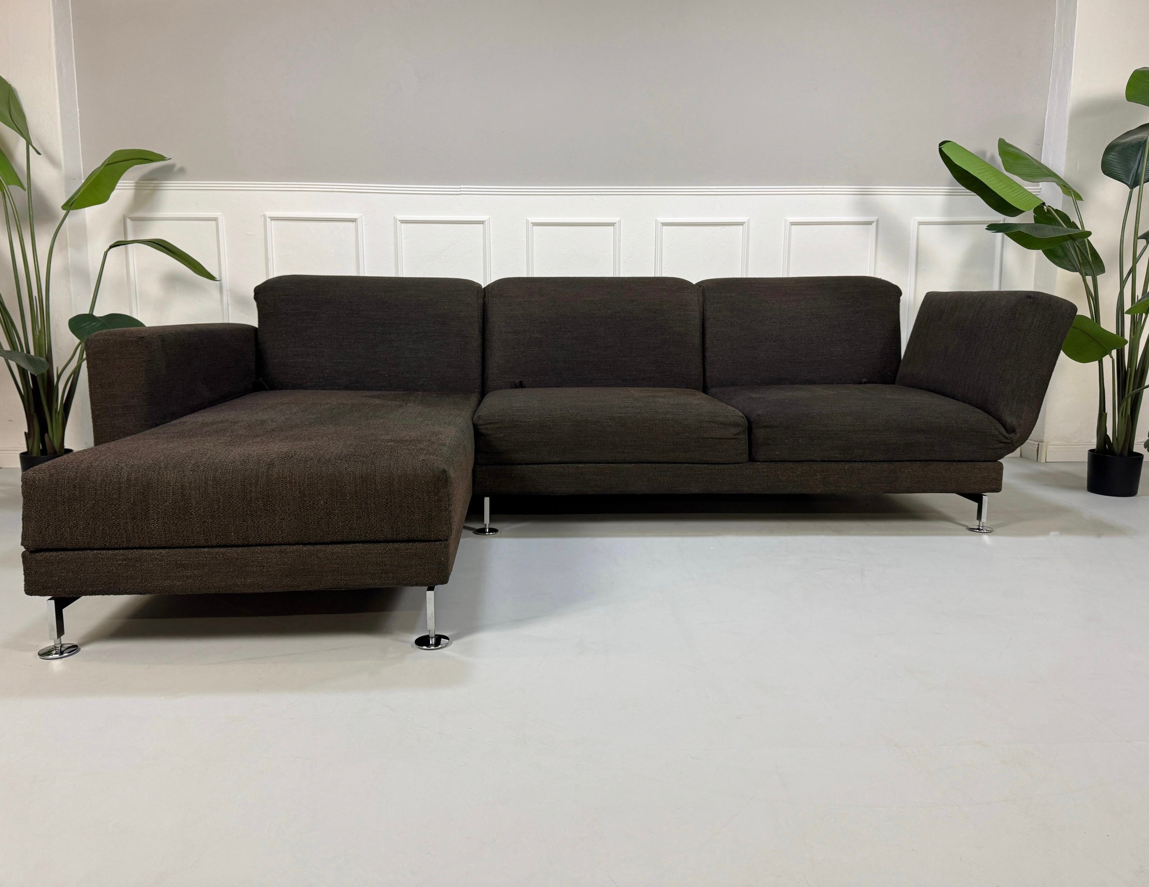 Gebrauchtes braunes Brühl Moule Designer Stoff Sofa vor einer Wand, stilvoll und modern eingerichtet.