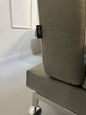 Gebrauchtes graues Brühl Moule Designer Stoff Sofa vor einer Wand, stilvoll und modern eingerichtet.
