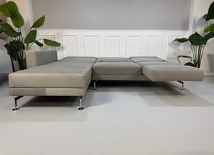 Gebrauchtes graues Brühl Moule Designer Stoff Sofa vor einer Wand, stilvoll und modern eingerichtet.