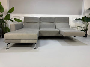 Gebrauchtes graues Brühl Moule Designer Stoff Sofa vor einer Wand, stilvoll und modern eingerichtet.
