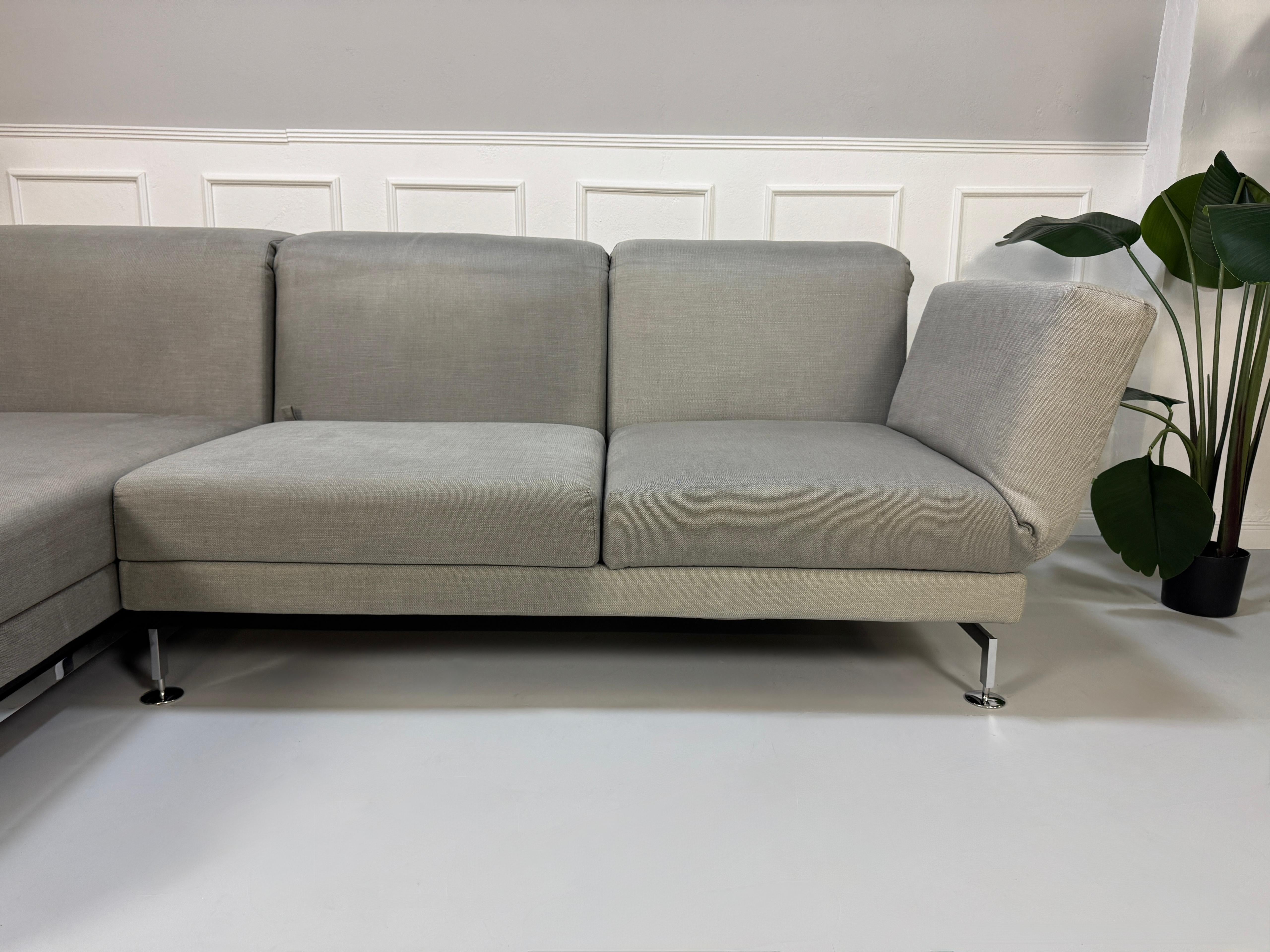 Gebrauchtes graues Brühl Moule Designer Stoff Sofa vor einer Wand, stilvoll und modern eingerichtet.