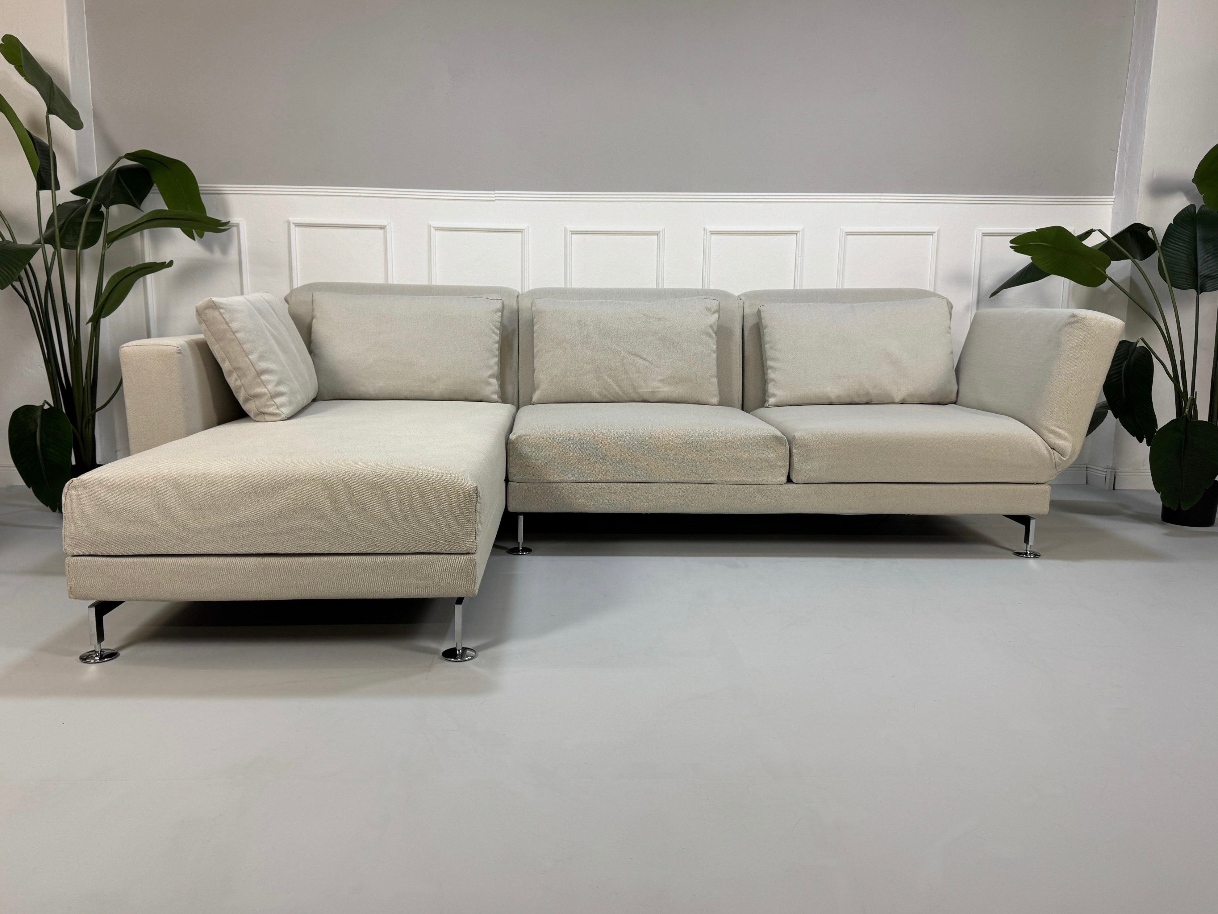 Gebrauchtes graues Brühl Moule Designer Stoff Sofa vor einer Wand, stilvoll und modern eingerichtet.
