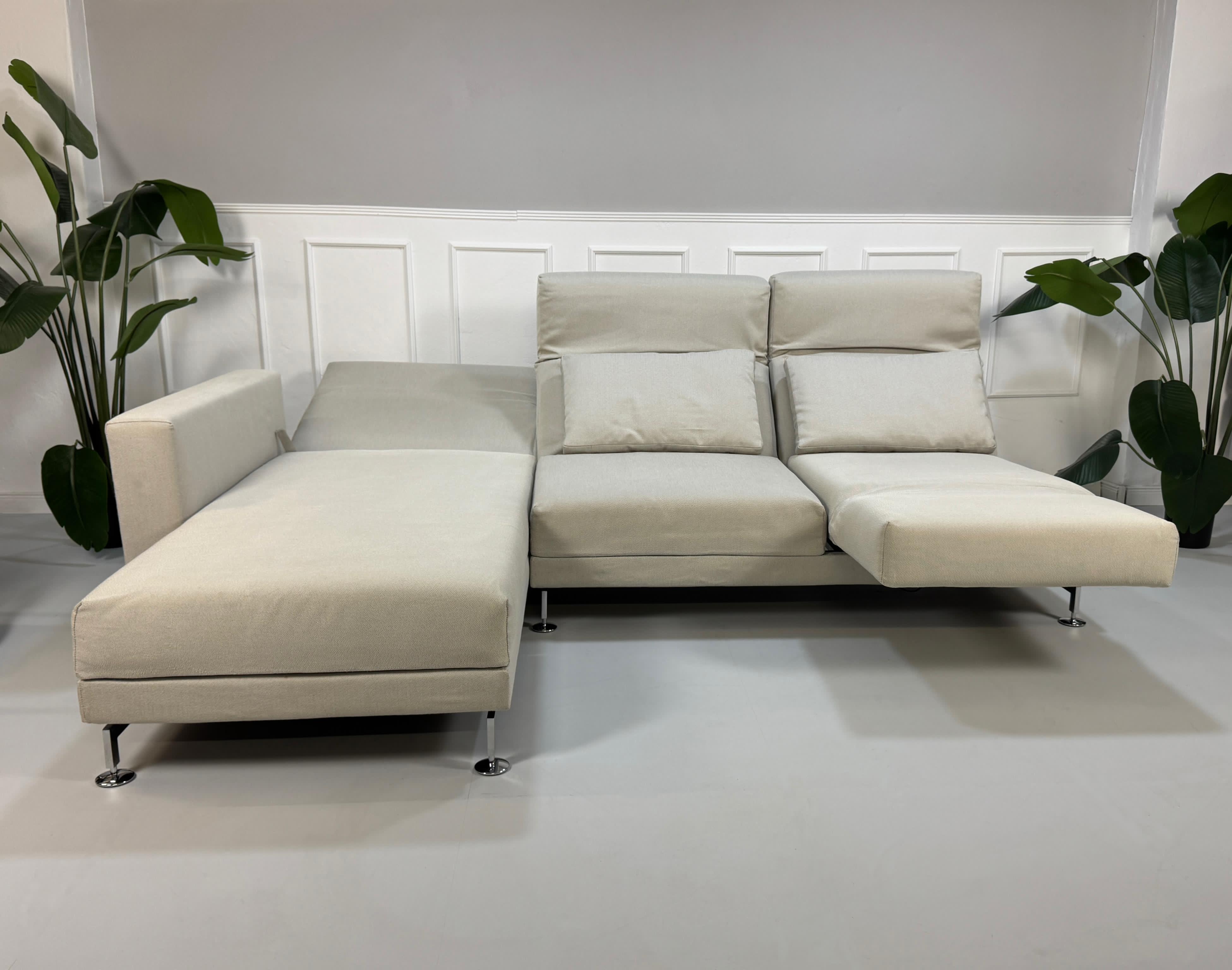 Gebrauchtes graues Brühl Moule Designer Stoff Sofa vor einer Wand, stilvoll und modern eingerichtet.