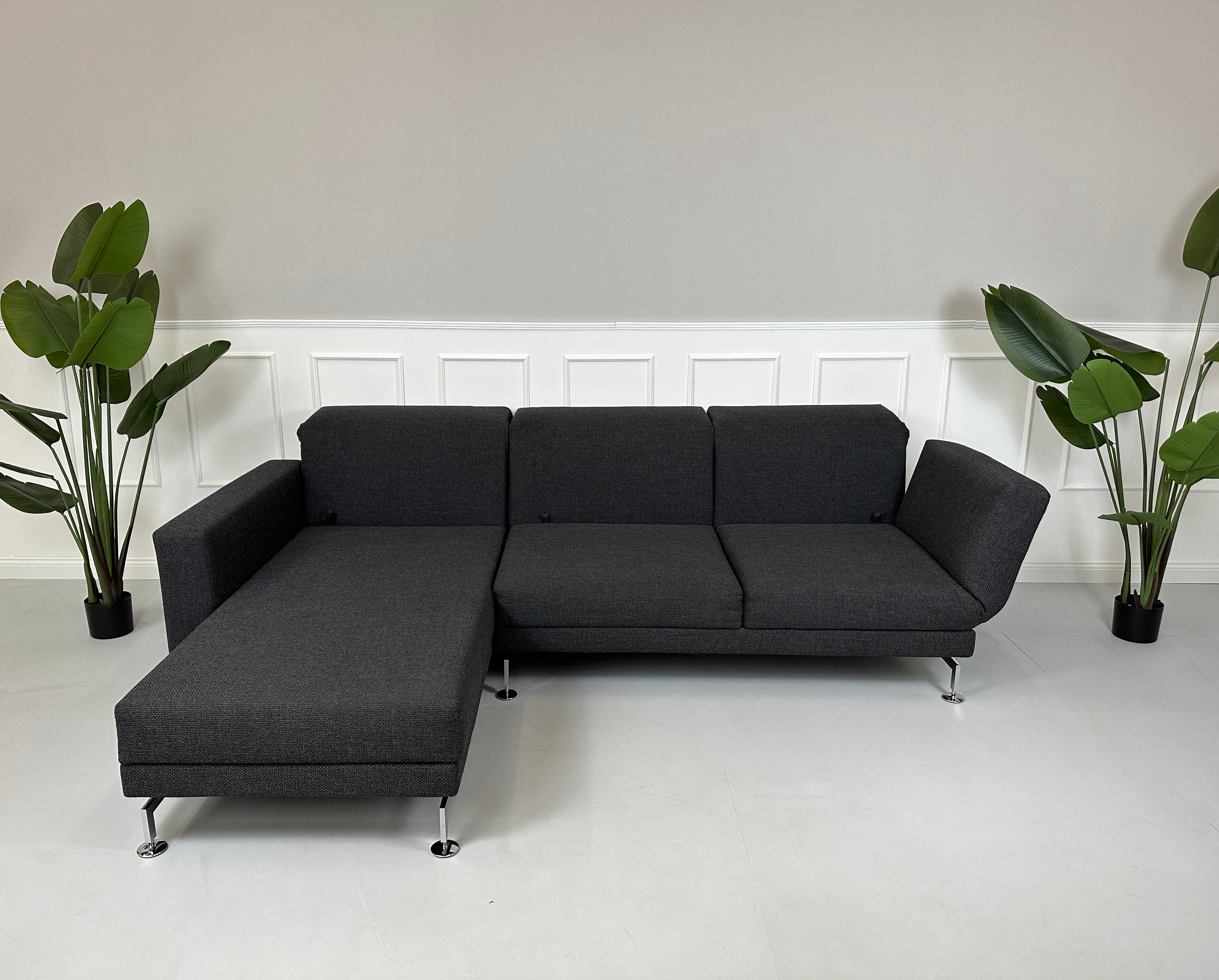 Gebrauchtes graues Brühl Moule Designer Stoff Sofa mit Hocker vor einer Wand, stilvoll und modern eingerichtet.