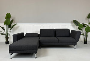 Gebrauchtes graues Brühl Moule Designer Stoff Sofa mit Hocker vor einer Wand, stilvoll und modern eingerichtet.