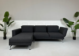 Gebrauchtes graues Brühl Moule Designer Stoff Sofa mit Hocker vor einer Wand, stilvoll und modern eingerichtet.