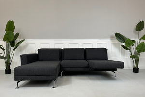 Gebrauchtes graues Brühl Moule Designer Stoff Sofa mit Hocker vor einer Wand, stilvoll und modern eingerichtet.