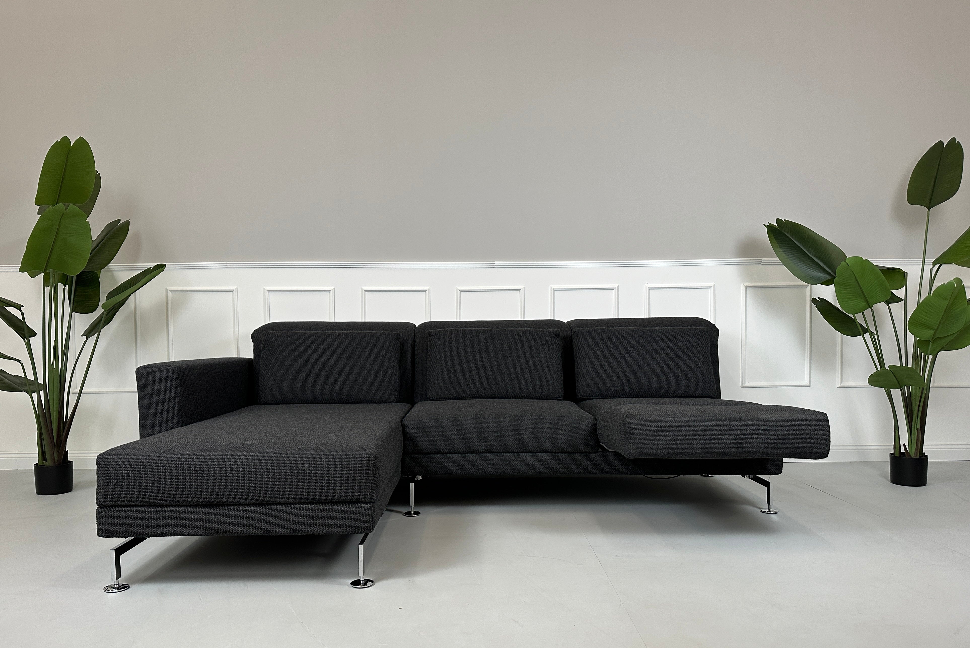 Gebrauchtes graues Brühl Moule Designer Stoff Sofa mit Hocker vor einer Wand, stilvoll und modern eingerichtet.