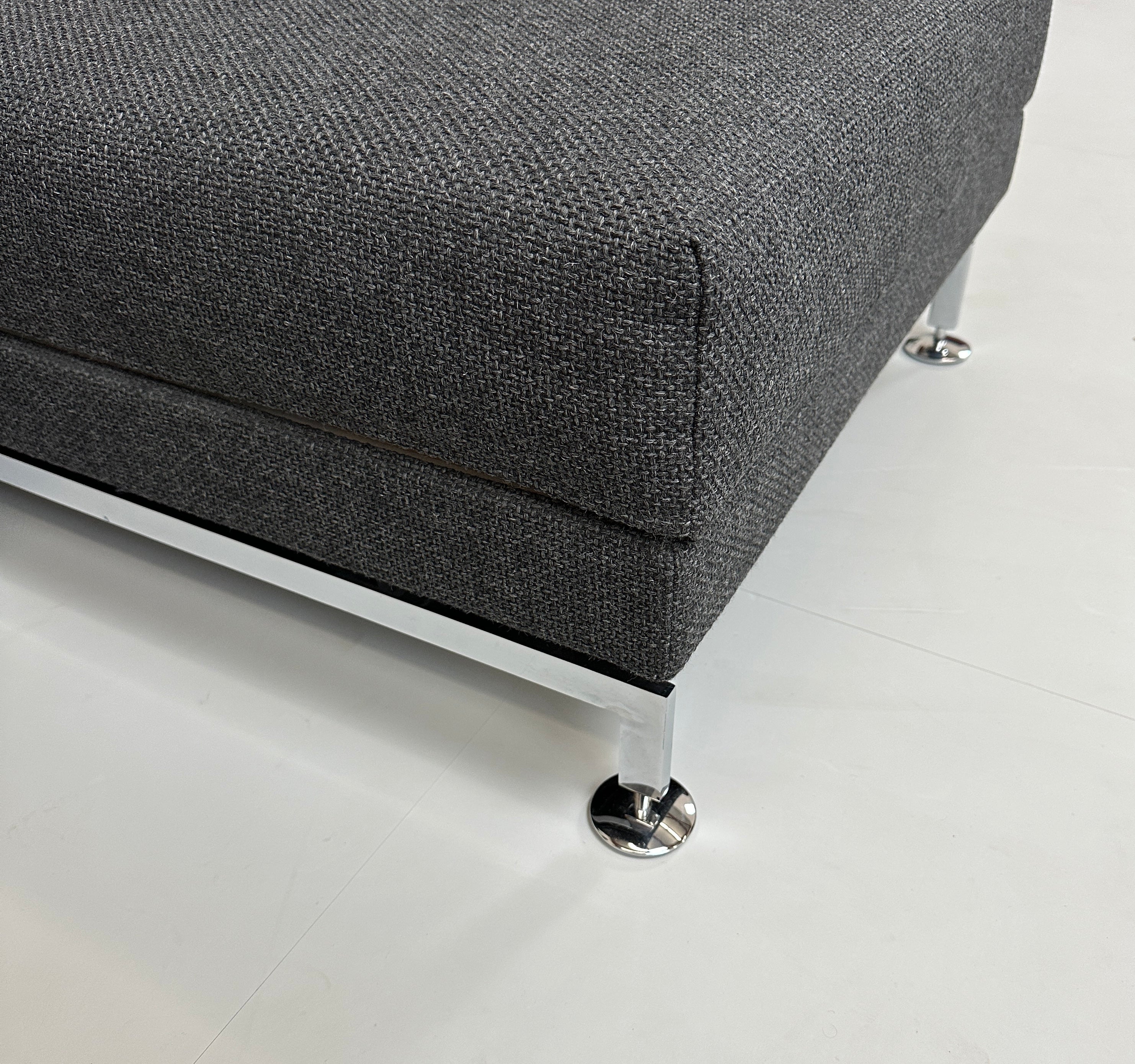 Gebrauchtes graues Brühl Moule Designer Stoff Sofa mit Hocker vor einer Wand, stilvoll und modern eingerichtet.