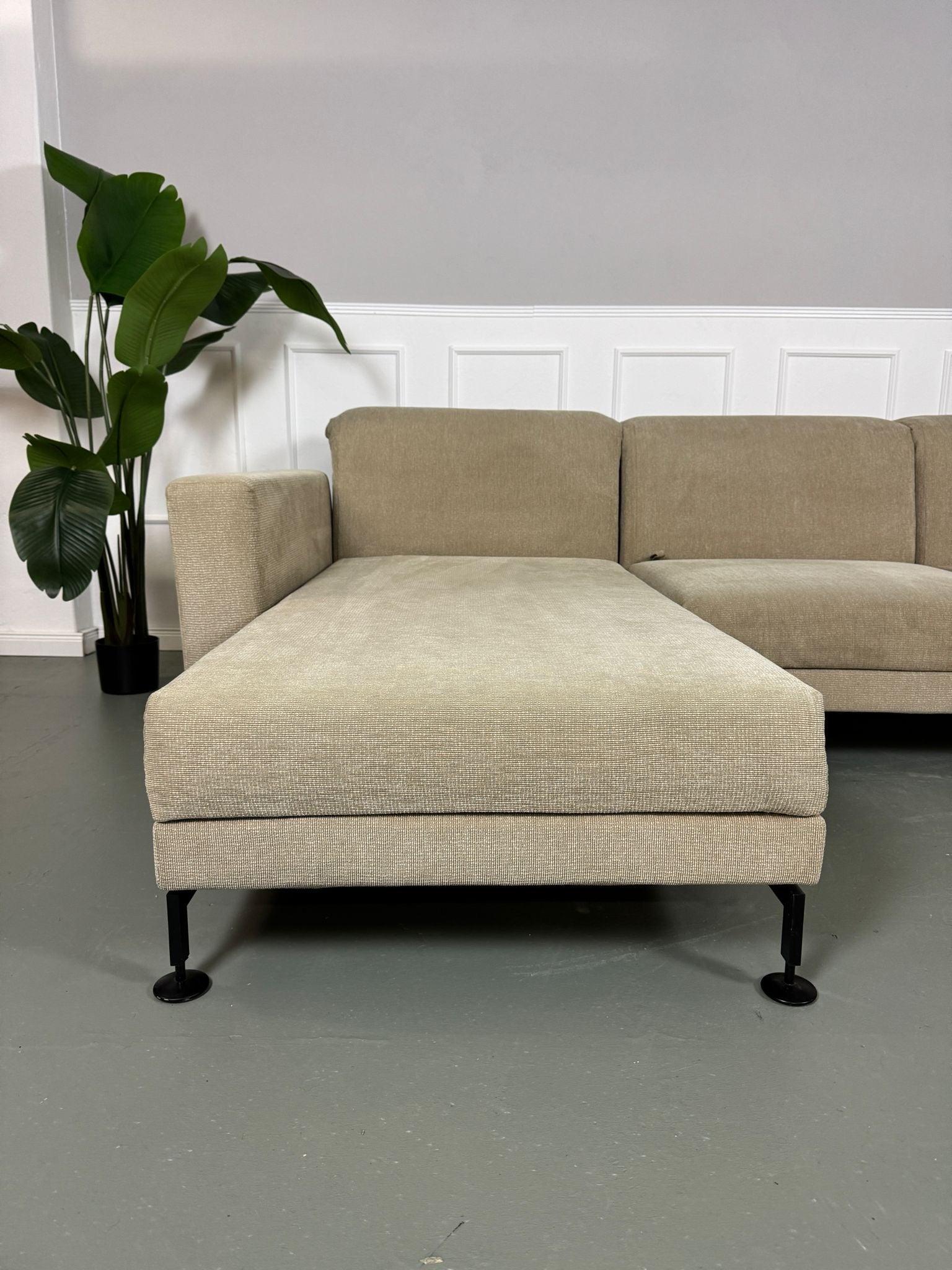 Gebrauchtes Brühl Moule Ecksofa Stoff in der Farbe Beige vor einer Wand, stilvoll und modern eingerichtet.