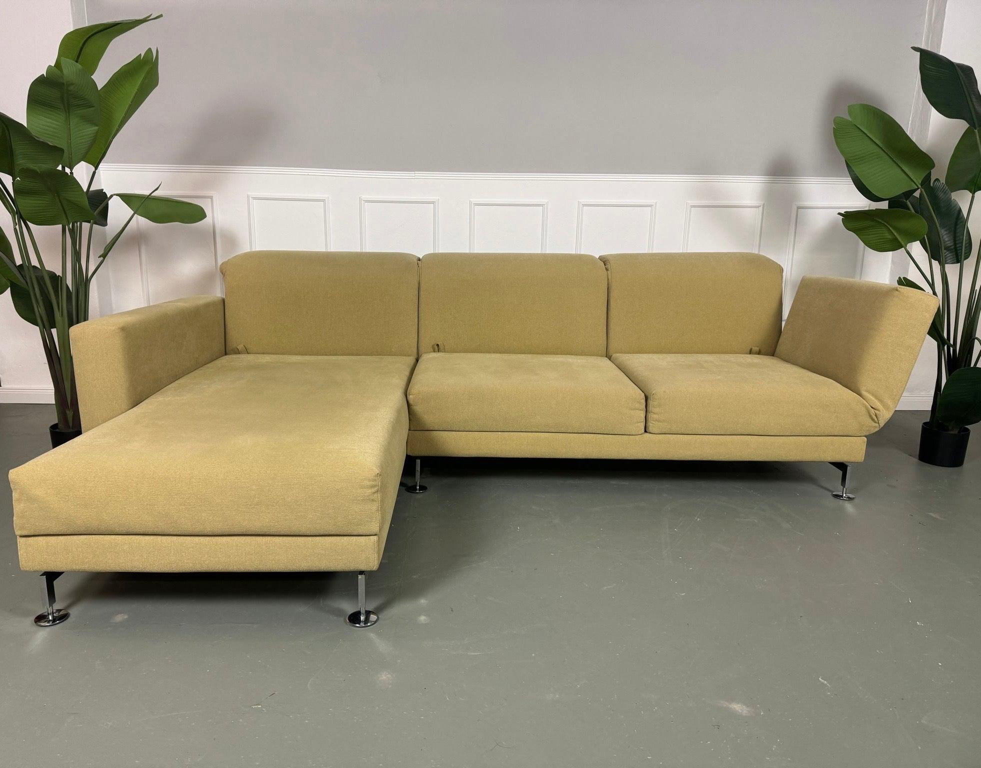 Gebrauchtes Brühl Moule Ecksofa Stoff in der Farbe Grün Beige vor einer Wand, stilvoll und modern eingerichtet.