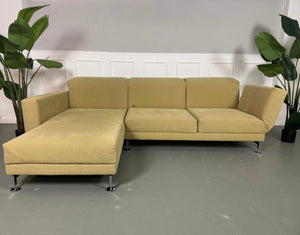 Gebrauchtes Brühl Moule Ecksofa Stoff in der Farbe Grün Beige vor einer Wand, stilvoll und modern eingerichtet.