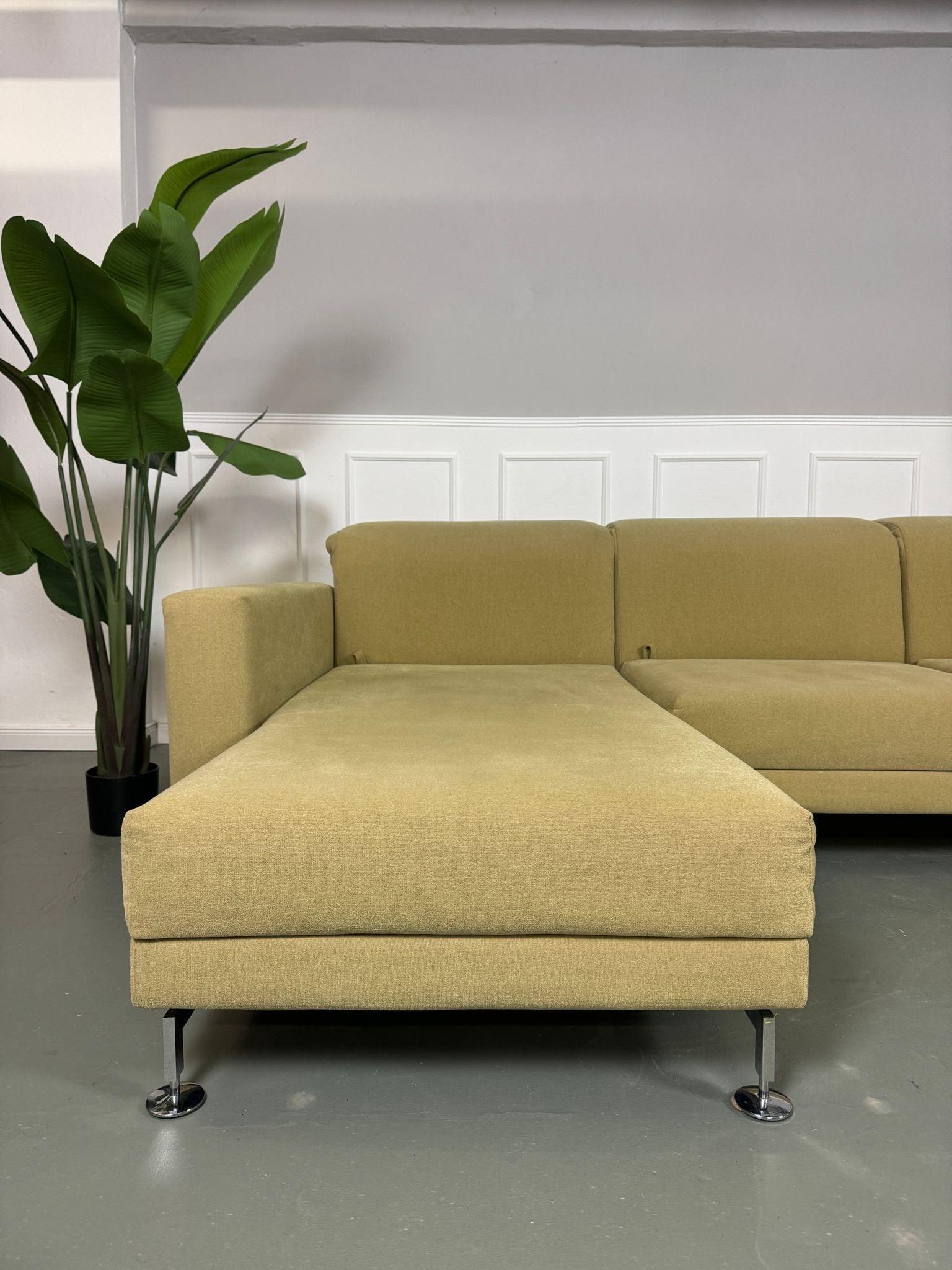 Gebrauchtes Brühl Moule Ecksofa Stoff in der Farbe Grün Beige vor einer Wand, stilvoll und modern eingerichtet.