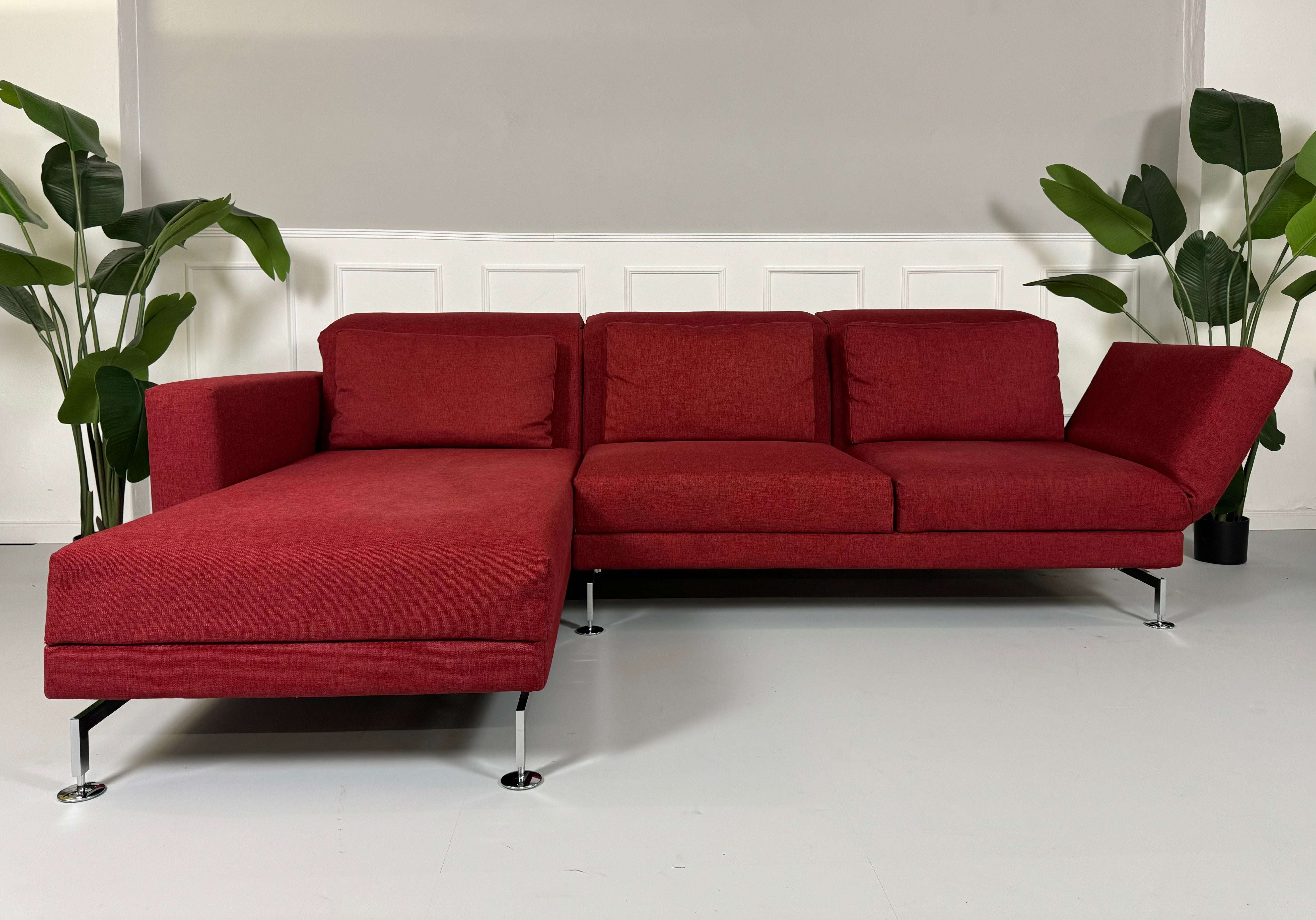 Gebrauchtes Brühl Moule Ecksofa Stoff in der Farbe Rot vor einer Wand, stilvoll und modern eingerichtet.