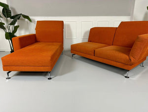 Gebrauchtes Brühl Moule Ecksofa Stoff in der Farbe Orange vor einer Wand, stilvoll und modern eingerichtet.