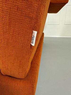 Gebrauchtes Brühl Moule Ecksofa Stoff in der Farbe Orange vor einer Wand, stilvoll und modern eingerichtet.