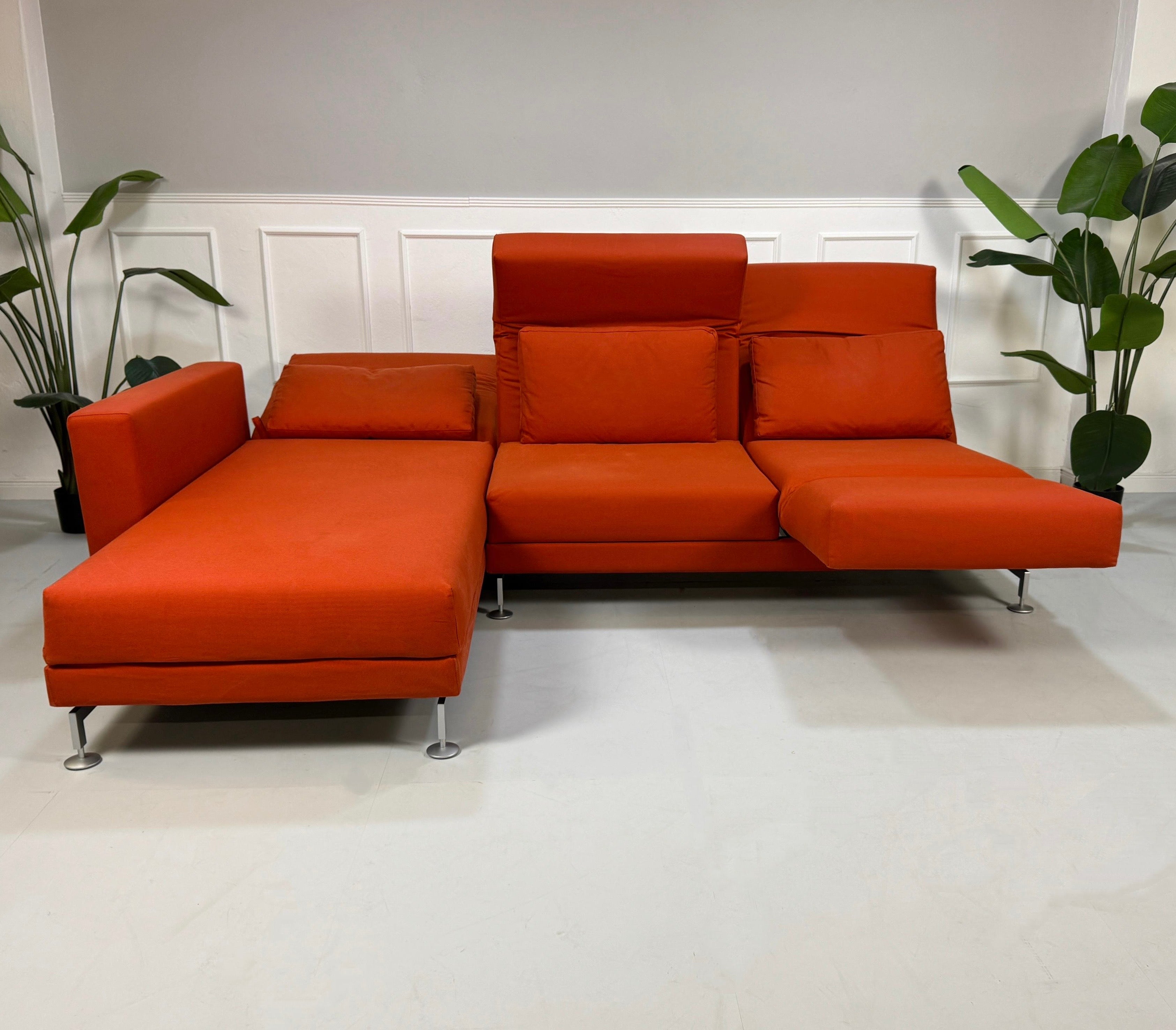 Gebrauchtes oranges Brühl Moule Designer Stoff Sofa vor einer Wand, stilvoll und modern eingerichtet.