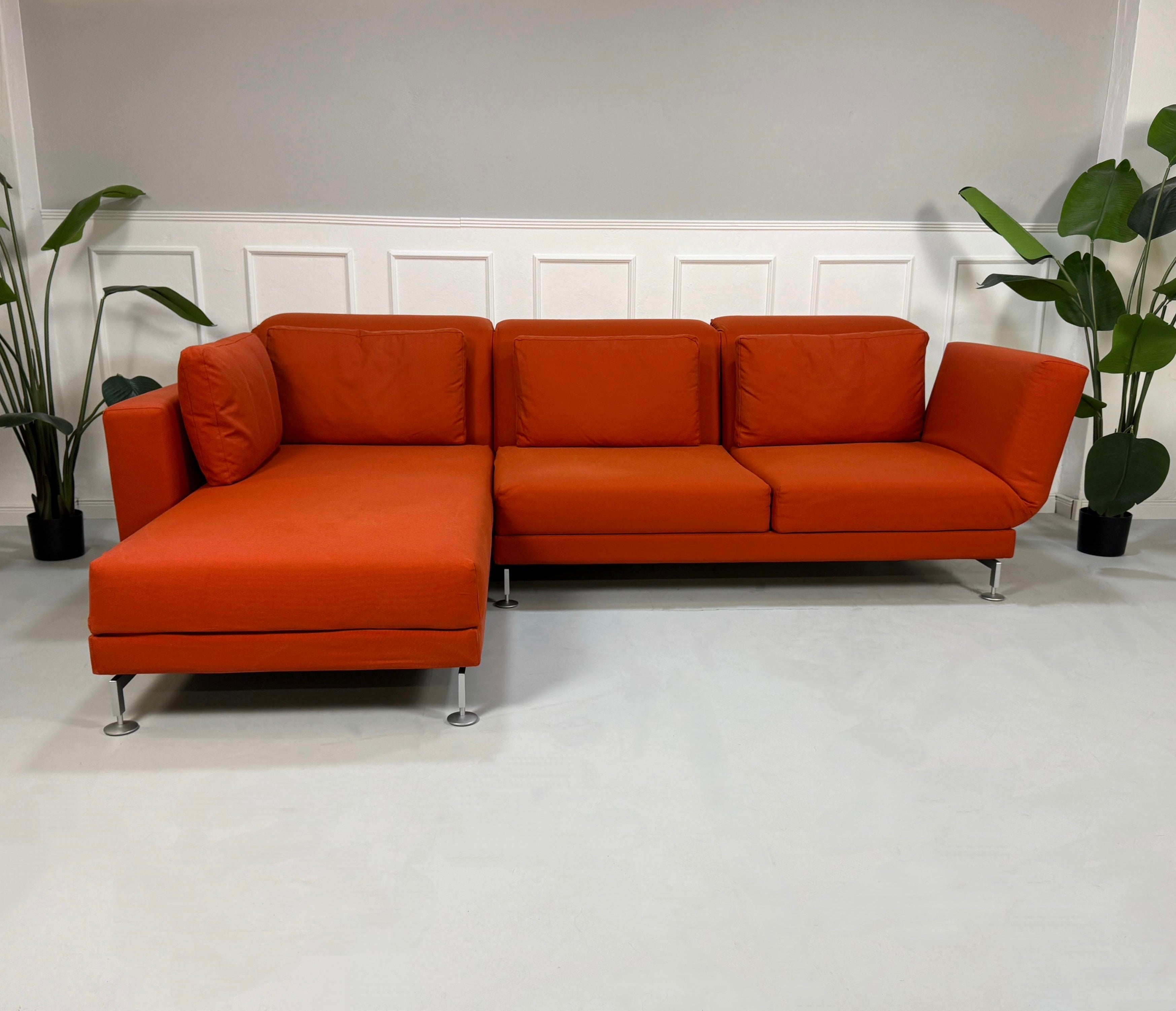 Gebrauchtes oranges Brühl Moule Designer Stoff Sofa vor einer Wand, stilvoll und modern eingerichtet.