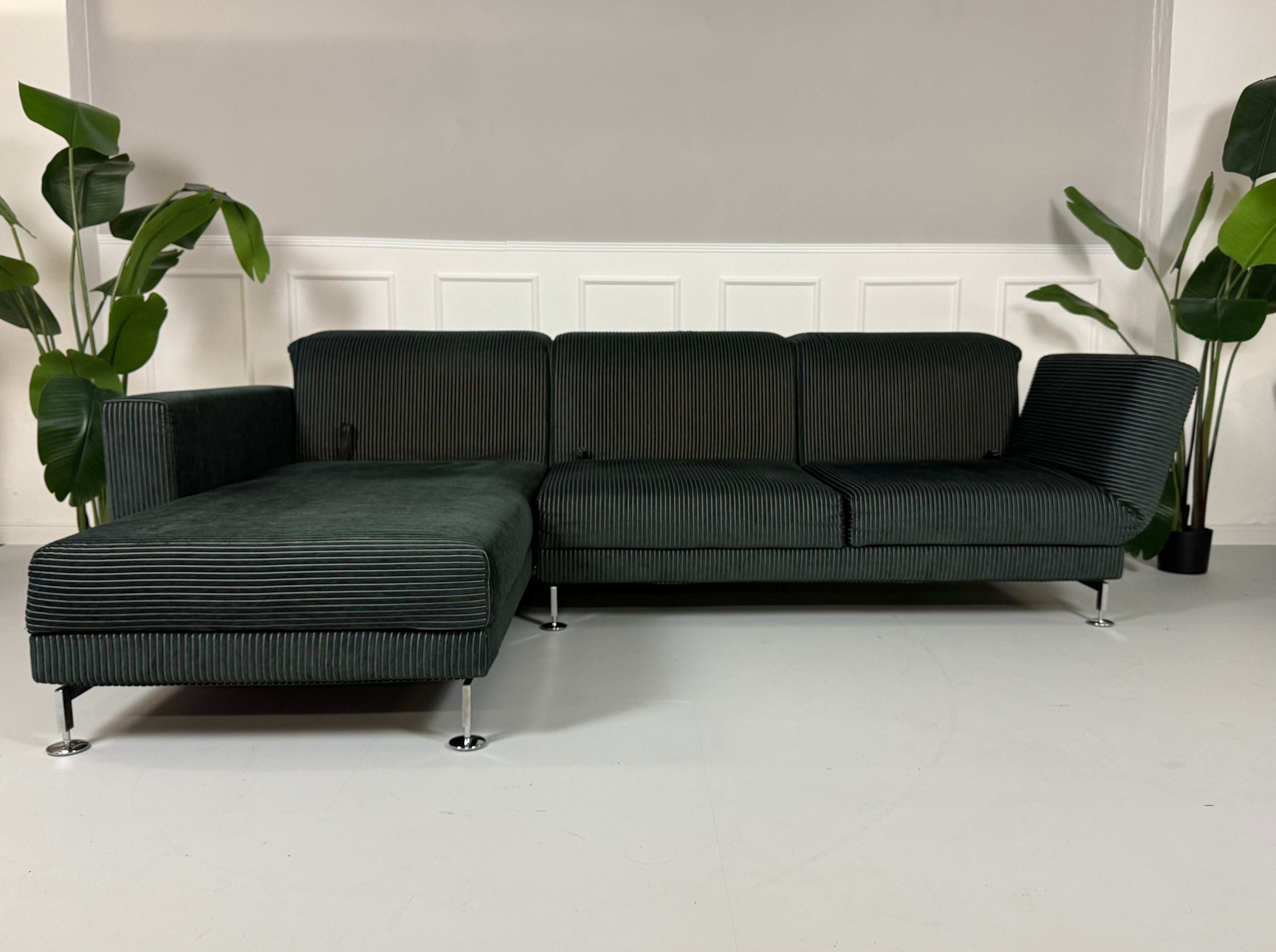 Gebrauchtes Brühl Moule Ecksofa Kord Stoff in der Farbe Schwarz vor einer Wand, stilvoll und modern eingerichtet.