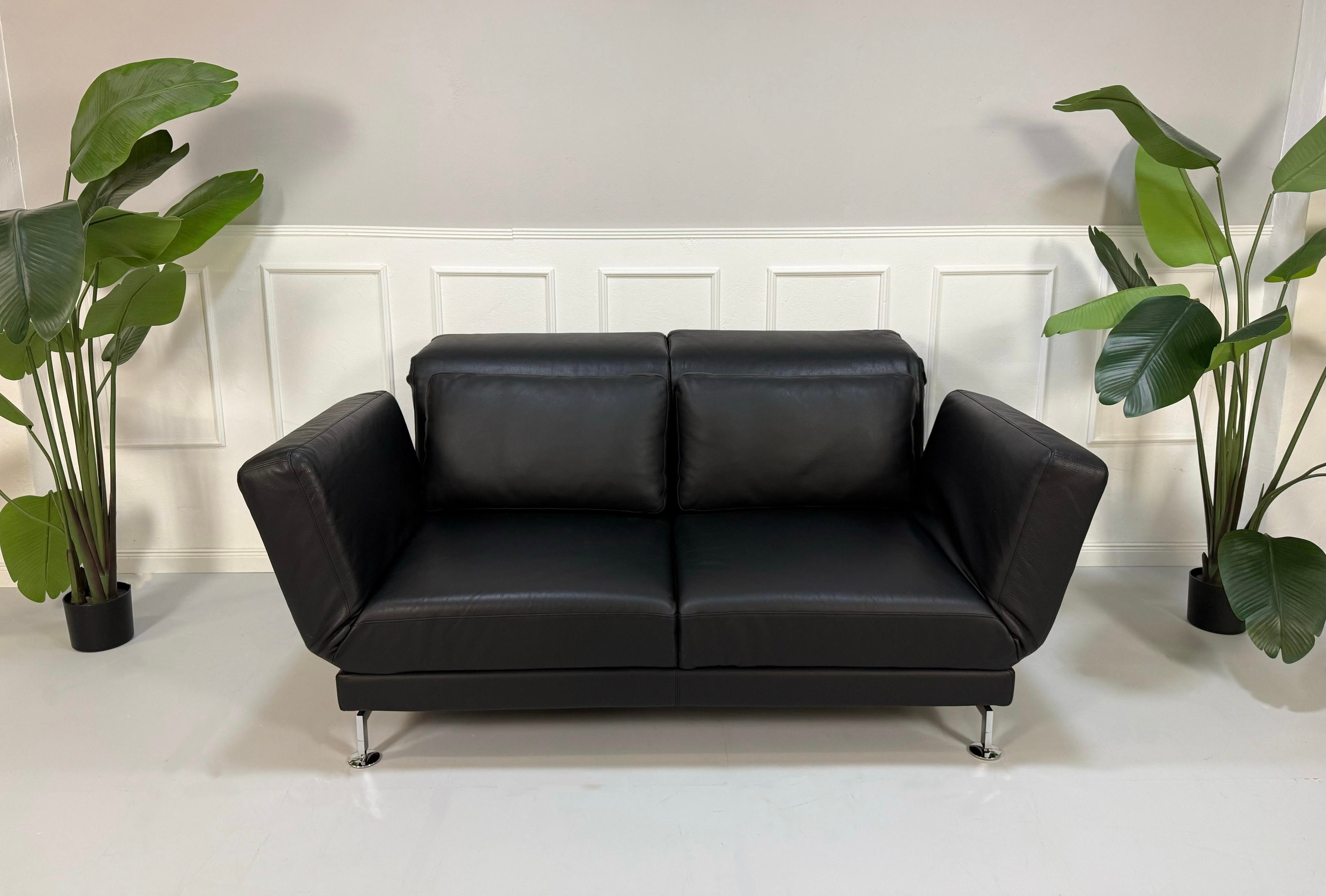 Gebrauchtes schwarzes Brühl Moule Designer Leder Sofa vor einer Wand, stilvoll und modern eingerichtet.