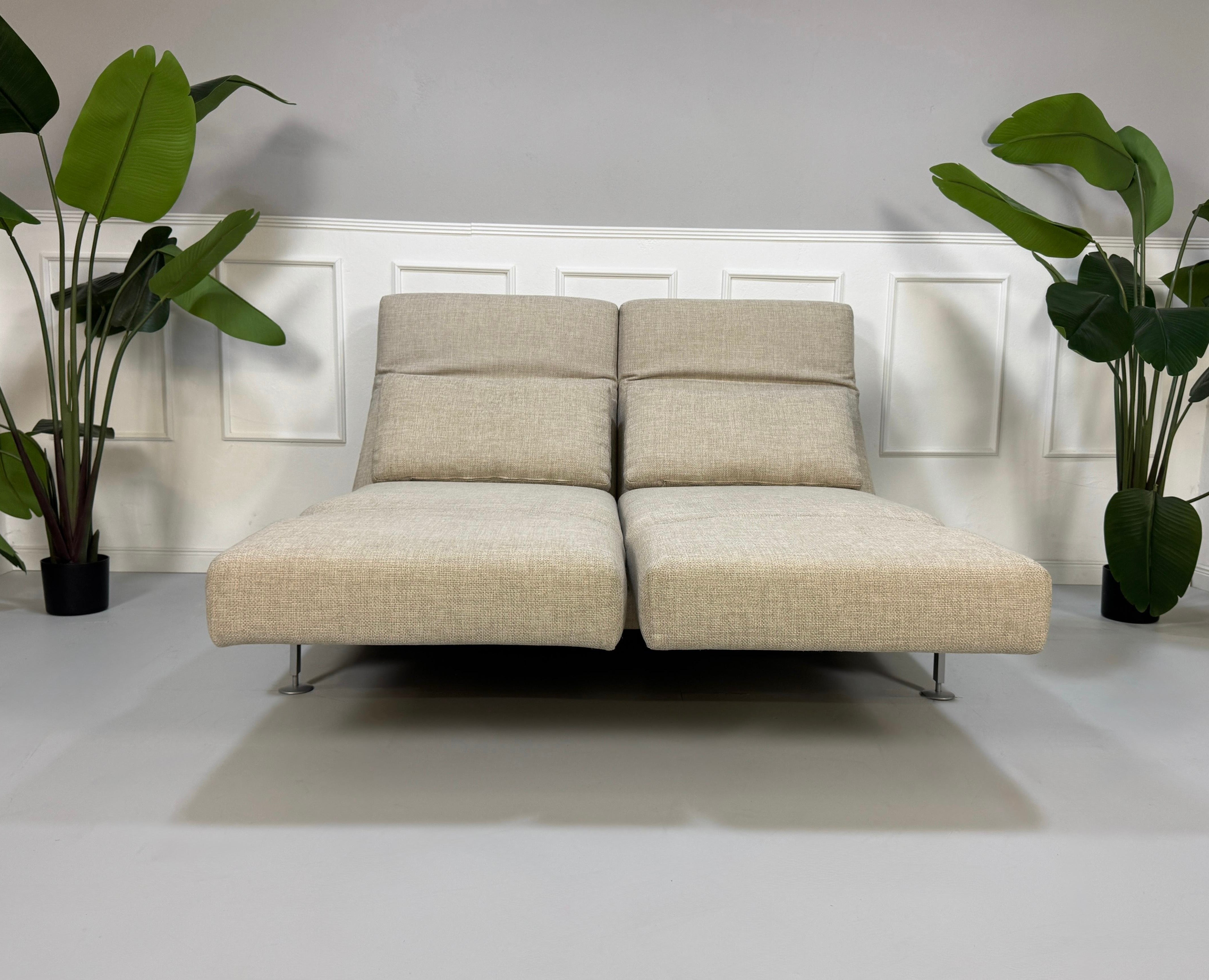 Gebrauchtes beiges Brühl Moule Designer Stoff Sofa vor einer Wand, stilvoll und modern eingerichtet.