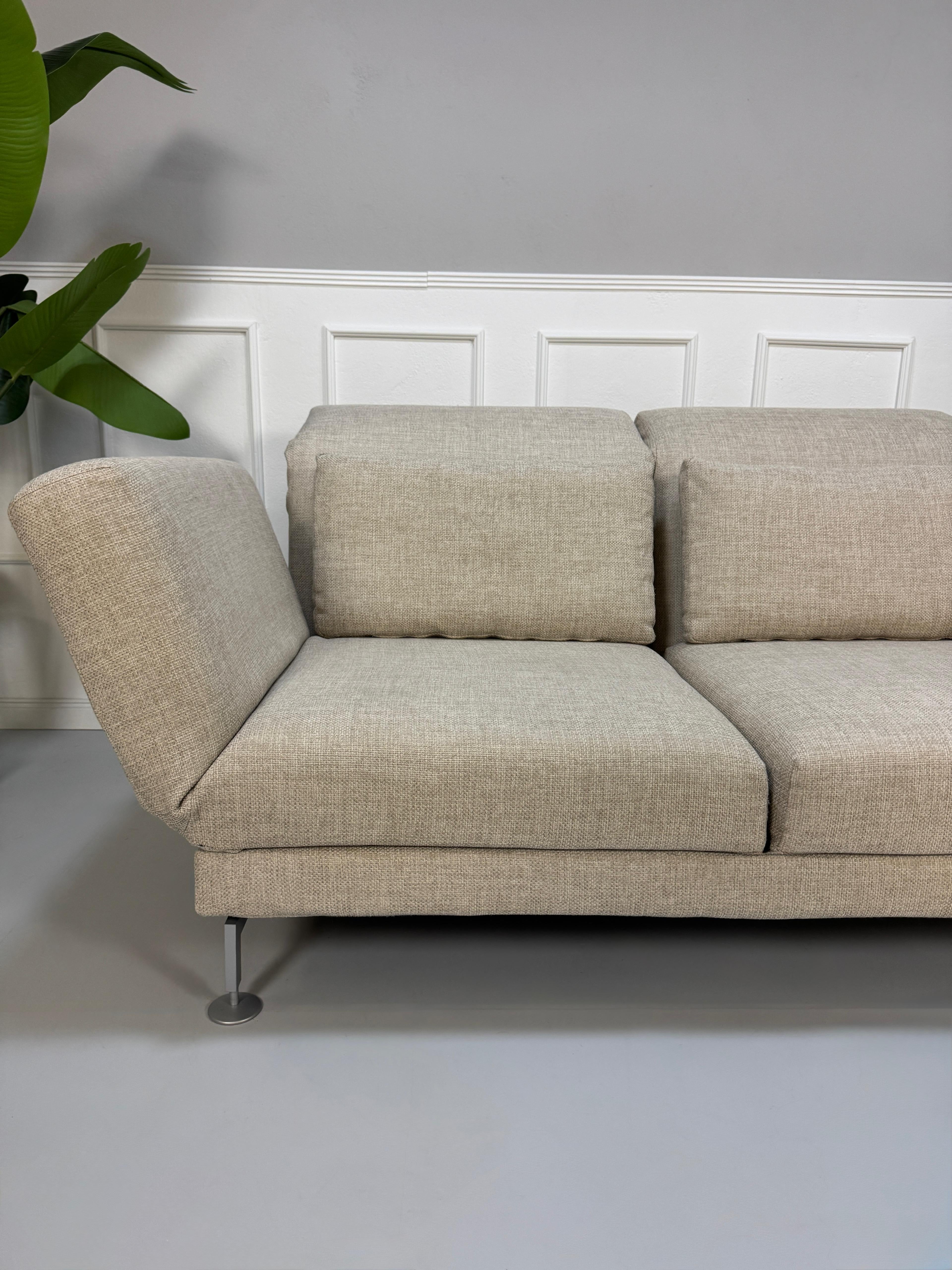 Gebrauchtes beiges Brühl Moule Designer Stoff Sofa vor einer Wand, stilvoll und modern eingerichtet.