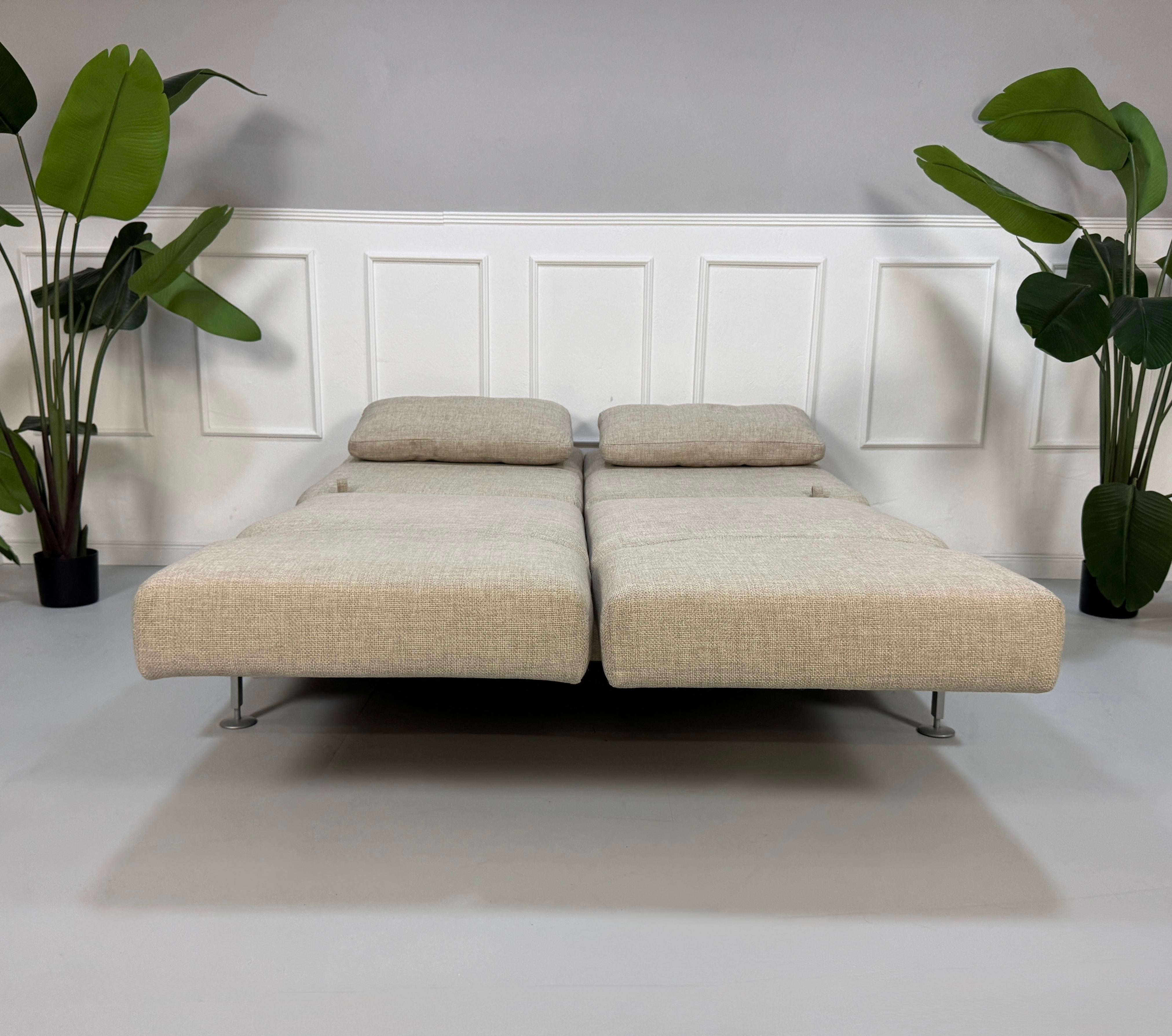 Gebrauchtes beiges Brühl Moule Designer Stoff Sofa vor einer Wand, stilvoll und modern eingerichtet.