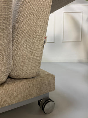 Gebrauchtes beiges Brühl Moule Designer Stoff Sofa vor einer Wand, stilvoll und modern eingerichtet.