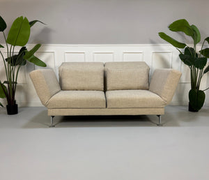 Gebrauchtes beiges Brühl Moule Designer Stoff Sofa vor einer Wand, stilvoll und modern eingerichtet.