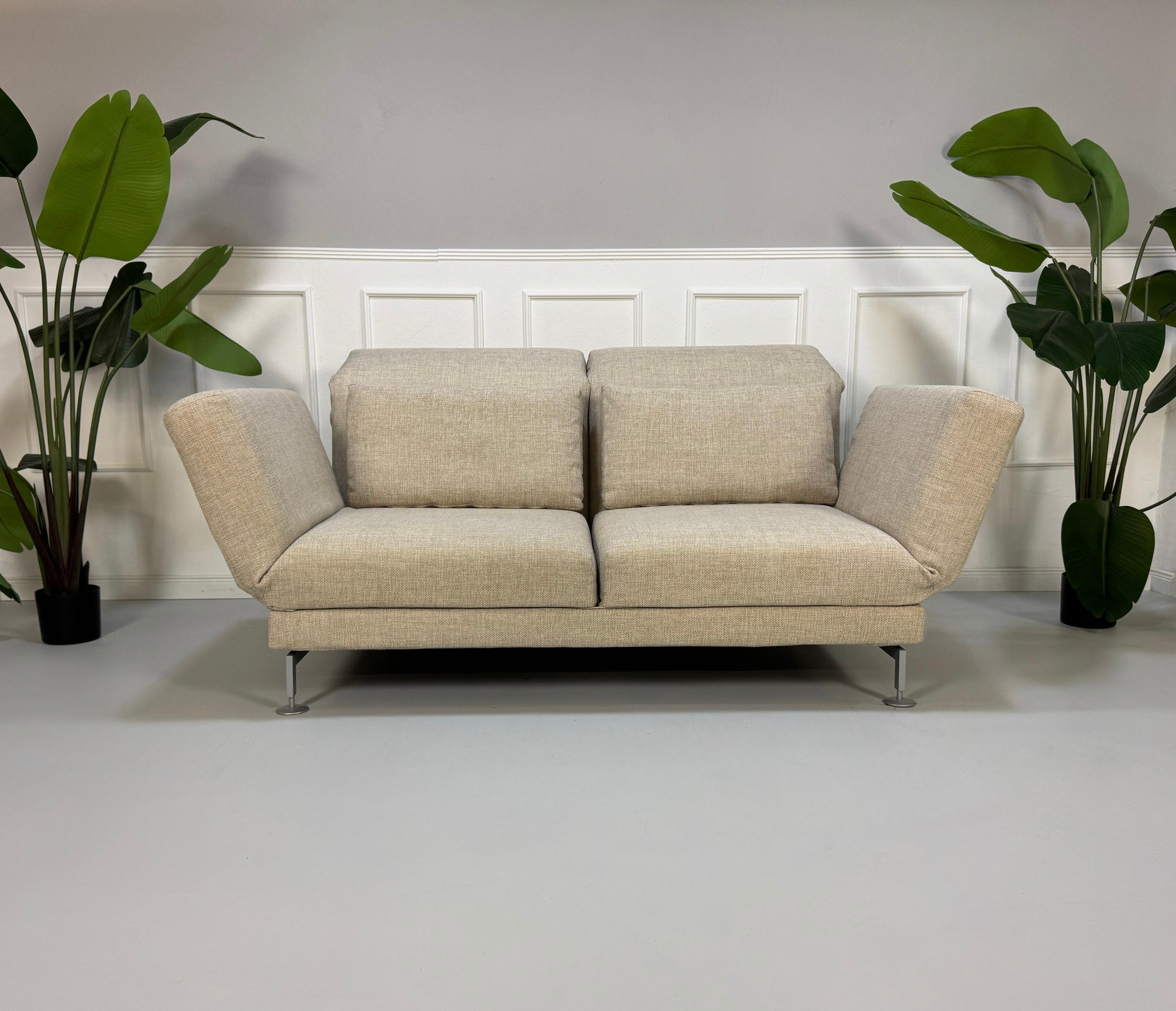 Gebrauchtes beiges Brühl Moule Designer Stoff Sofa vor einer Wand, stilvoll und modern eingerichtet.
