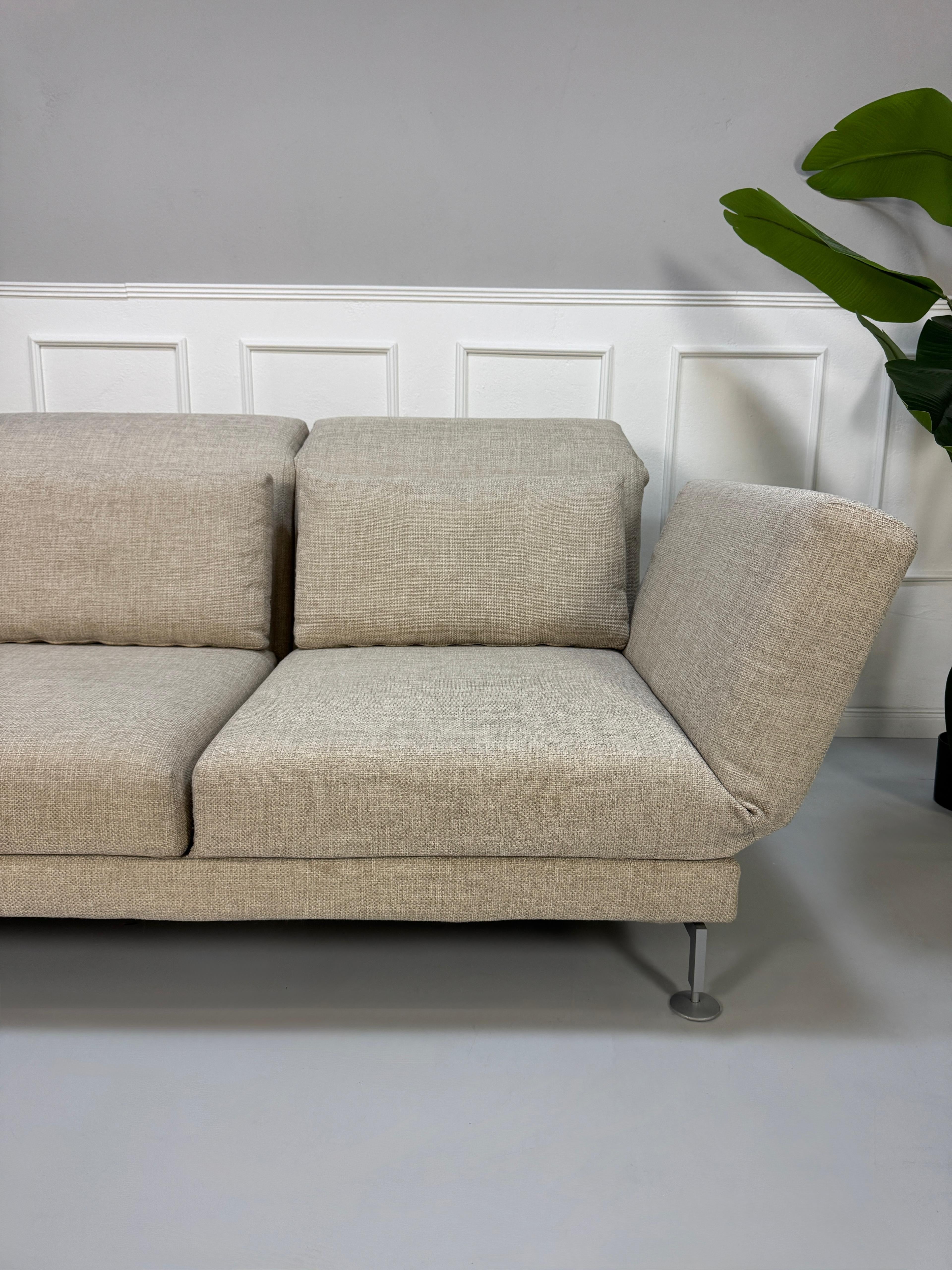 Gebrauchtes beiges Brühl Moule Designer Stoff Sofa vor einer Wand, stilvoll und modern eingerichtet.