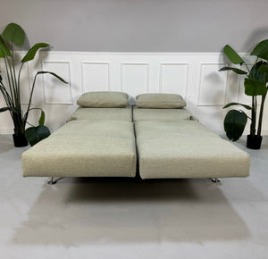 Gebrauchtes beiges Brühl Moule Designer Stoff Sofa vor einer Wand, stilvoll und modern eingerichtet.