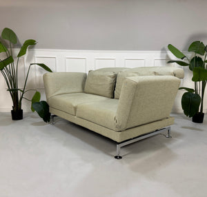 Gebrauchtes beiges Brühl Moule Designer Stoff Sofa vor einer Wand, stilvoll und modern eingerichtet.
