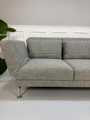 Refurbished graues Brühl Moule Designer Stoff Sofa vor einer Wand, stilvoll und modern eingerichtet.