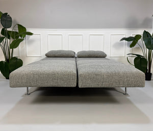 Refurbished graues Brühl Moule Designer Stoff Sofa vor einer Wand, stilvoll und modern eingerichtet.